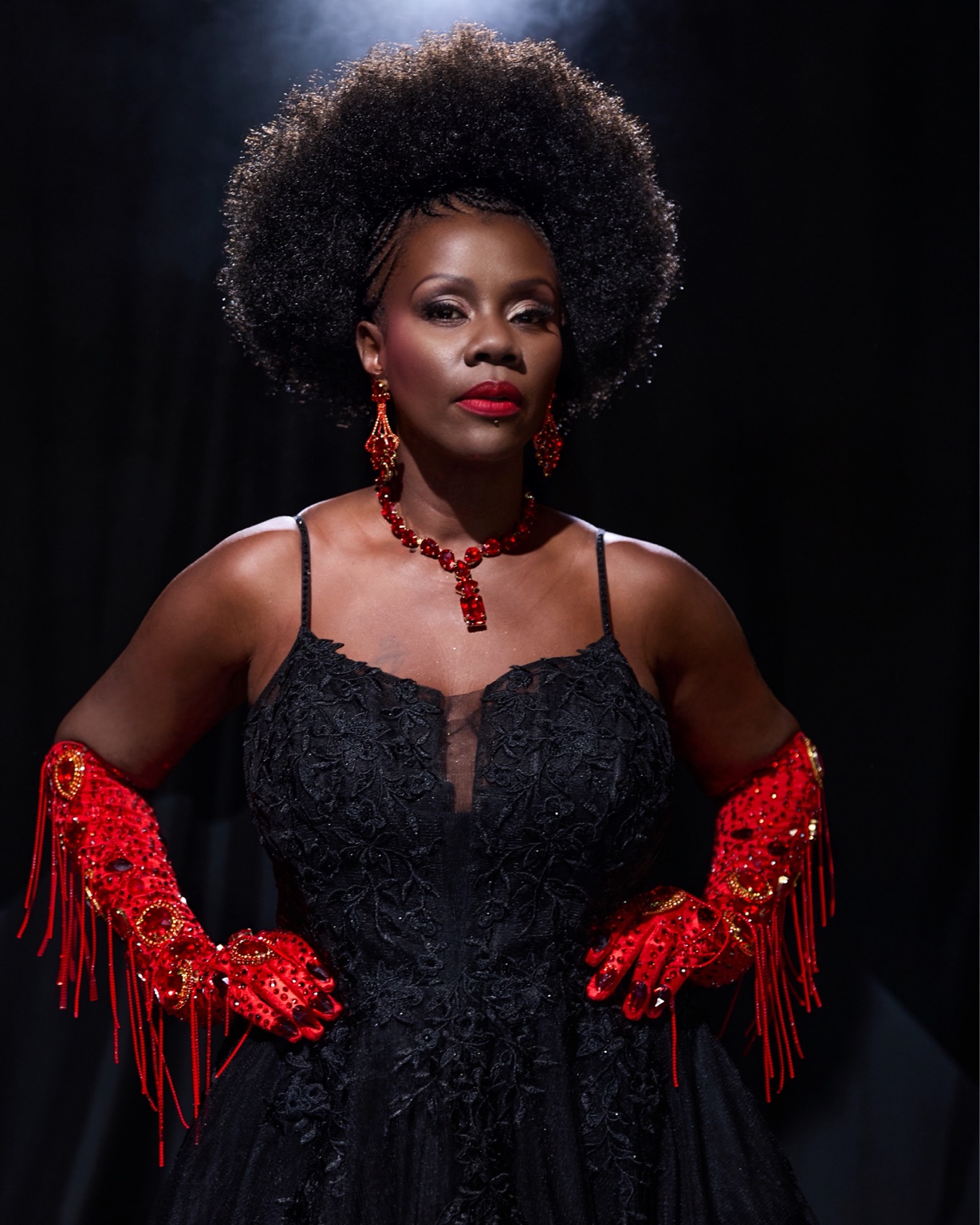 Cynthia in an elegant black pageant gown with red gloves